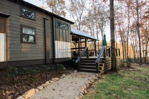 a house with a porch and a staircase next to it at Still Waters Tiny Home in Tracy City