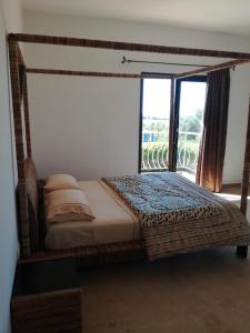 a bedroom with a canopy bed with a large window at Brise de Tamaris in Oulad Akkou
