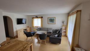 a living room with a couch and a table and chairs at Ferienwohnung Engadin Barbey in Zuoz