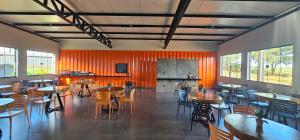 a restaurant with tables and chairs and a kitchen at Village Hotel Container in Sidrolândia