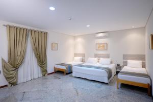 a bedroom with two beds and a window at Colonial Plaza Hotel Pindamonhangaba in Pindamonhangaba
