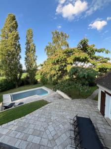 einen Hinterhof mit einem Pool und einer Steinterrasse in der Unterkunft Villa Relax avec Piscine Privée à 90 min de Paris in Saint-Hilaire-les-Andrésis + 99 Fotos
