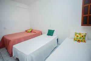 two beds in a room with white walls at Pousada dos Girassois Trancoso in Porto Seguro