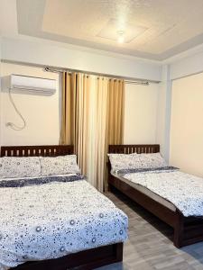 a bedroom with two beds and a curtain at Mountain Cove Villa in Pagudpud