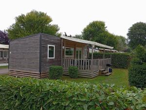 a small cabin with a porch in a yard at Mobilhome 6 places in Houlgate