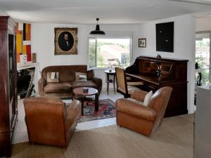 - un salon avec un piano et des meubles en cuir dans l'établissement La maison du cerf, à Bergues