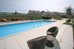 a swimming pool with two chairs next to at Villa Emilia 0206 P104 in Nieuwpoort