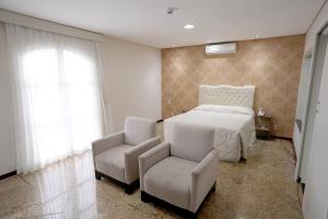 a bedroom with a bed and a chair at Colonial Plaza Hotel Pindamonhangaba in Pindamonhangaba