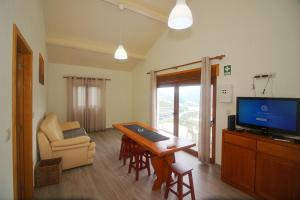 ein Wohnzimmer mit einem TV, einem Tisch und einem Stuhl in der Unterkunft Casa da Carvalha Mona in Rio Caldo