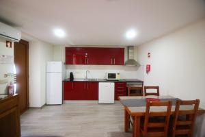 eine Küche mit roten Schränken und einem Tisch und eine Küche mit einem Tableablish in der Unterkunft Casa da Carvalha Mona in Rio Caldo