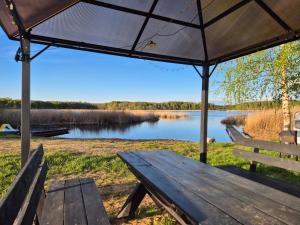 a picnic table with an umbrella in front of a lake at Telšu vieta Sīvera Medniekkrasti 