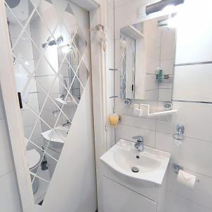 een witte badkamer met een wastafel en een spiegel bij Cute studio-great location in Zadar