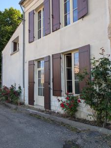 un edificio con persiane in legno e fiori sul lato di Maison au coeur du vignoble a Loupiac-de-Cadillac
