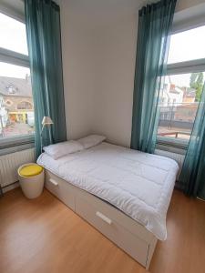 a bed in a room with two windows at Wohnung am Schlosspark in Bendorf