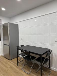 a black table and chairs in a room with a refrigerator at Casa de Ferias apartamento T3 in Carregado