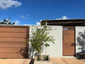 a house with two garage doors and a tree at Casa 2min do Centro c Piscina in Bonito +10 photos