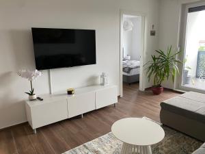 a white living room with a flat screen tv on a wall at Dream Apartment VG - Self Check in - Garage in Velika Gorica
