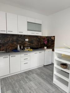 a white kitchen with white cabinets and a tile floor at Kares house in Belgrade