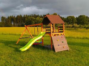 un parco giochi in legno con scivolo in un campo di AB Domki Pstrążna a Kudowa-Zdrój