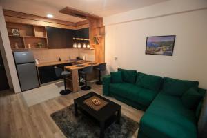 a living room with a green couch and a kitchen at Zeus Apartman in Jagodina