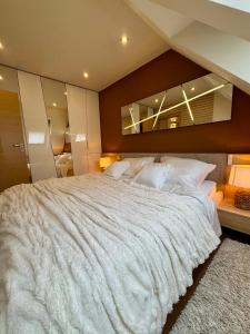a bedroom with a large white bed with a large mirror at AVIRA Apartman with Free Private Garage in Nyíregyháza