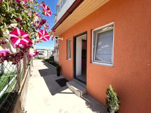 an orange building with a door and flowers on a fence at Studio Navae in Năvodari
