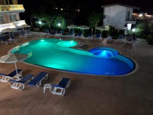 Una piscina de noche con sillas y sombrillas. en SEA WOLF Apartman Луксозен апартамент с панорамна гледка към морето климатик с нова напълно оборудвана кухня отделна баня с тоалетна гледка към басейна на 30 м от плажа Паркинг към хотела Навсякъде близо, en Lozenets