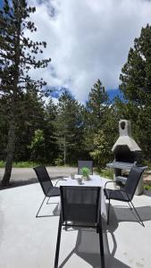 een terras met een tafel, stoelen en een open haard bij Forza Blidinje in Blidinje