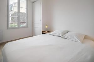 a white bed in a white bedroom with a window at Balnéo hyper centre, Calme, Equipé, Proche gare, Wifi in Troyes