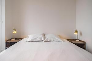 a white bed with two lamps on two tables at Balnéo hyper centre, Calme, Equipé, Proche gare, Wifi in Troyes