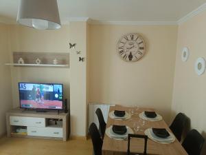 a dining room with a table and a clock on the wall at Piso PLAYA CANGAS CENTRO in Cangas de Morrazo