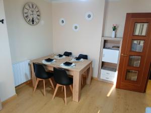 a dining room table with chairs and a clock on the wall at Piso PLAYA CANGAS CENTRO in Cangas de Morrazo