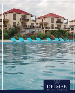 a pool with blue lounge chairs in front of buildings at Delmar resıdence in Mekhrably +10 photos