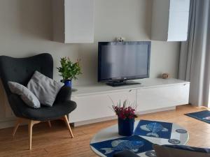 Una sala de estar con un televisor y una silla. en Apartament Blu Mare Pogorzelica, en Pogorzelica