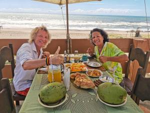 two older women sitting at a table with food on the beach at Bangalô Panorâmica in Conde