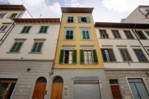 un edificio alto de color amarillo con ventanas con contraventanas verdes en Soggiorno Pezzati, en Florencia