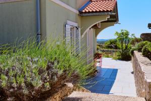 Una casa con un porche y algunas plantas al lado. en Green House, en Nerezine