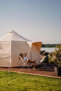 a woman sitting in a chair in front of a tent at Glamping Wake Surf Náklo in Olomouc