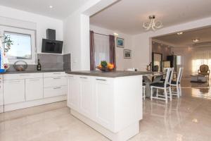a kitchen with white cabinets and a table in it at Vila Kathy - kuća za odmor in Seget Vranjica