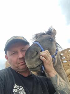 a man is kissing a small horse on its nose at Uszate Ranczo in Rybna