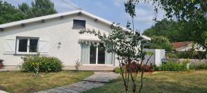 ein weißes Haus mit einem Baum davor in der Unterkunft Villa indépendante avec piscine in Arès