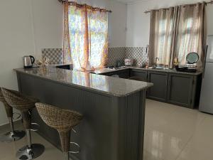 a kitchen with a counter with chairs and a counter top at Vacation House with Private Pool in Baie du Tombeau