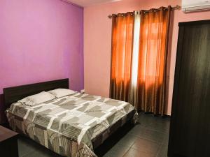 a bedroom with a bed with purple walls and a window at Vacation House with Private Pool in Baie du Tombeau