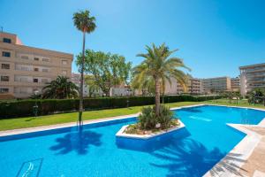 a large blue swimming pool with palm trees and buildings at Ona Aquamarina in La Pineda