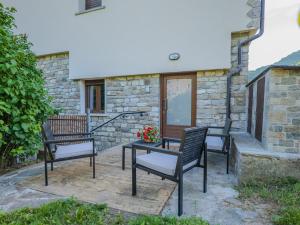 a patio with three chairs and a table with flowers at Ca di Borra - Orto Bio e Piscina in Rofelle