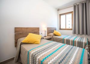 a bedroom with two beds and a window at Ona Aquamarina in La Pineda +16 photos