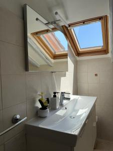 a bathroom with a sink with a mirror and a window at Accogliente Mansarda Vicino al Mare in Savona +15 photos