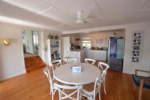 eine Küche und ein Esszimmer mit einem weißen Tisch und Stühlen in der Unterkunft The Mermaid's Tail in Pringle Bay