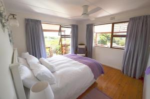 a bedroom with a bed with white pillows and windows at The Mermaid's Tail in Pringle Bay +17 photos