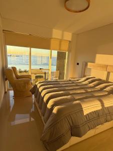 ein Schlafzimmer mit einem großen Bett und einem großen Fenster in der Unterkunft Despertar Frente al Mar in Puerto Madryn